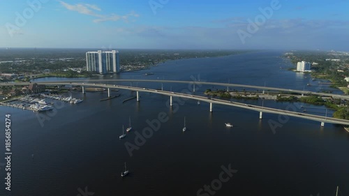 Long bridge crossing wide river with boats marina and waterfront buildings near Daytona Beach Florida on clear sunny day