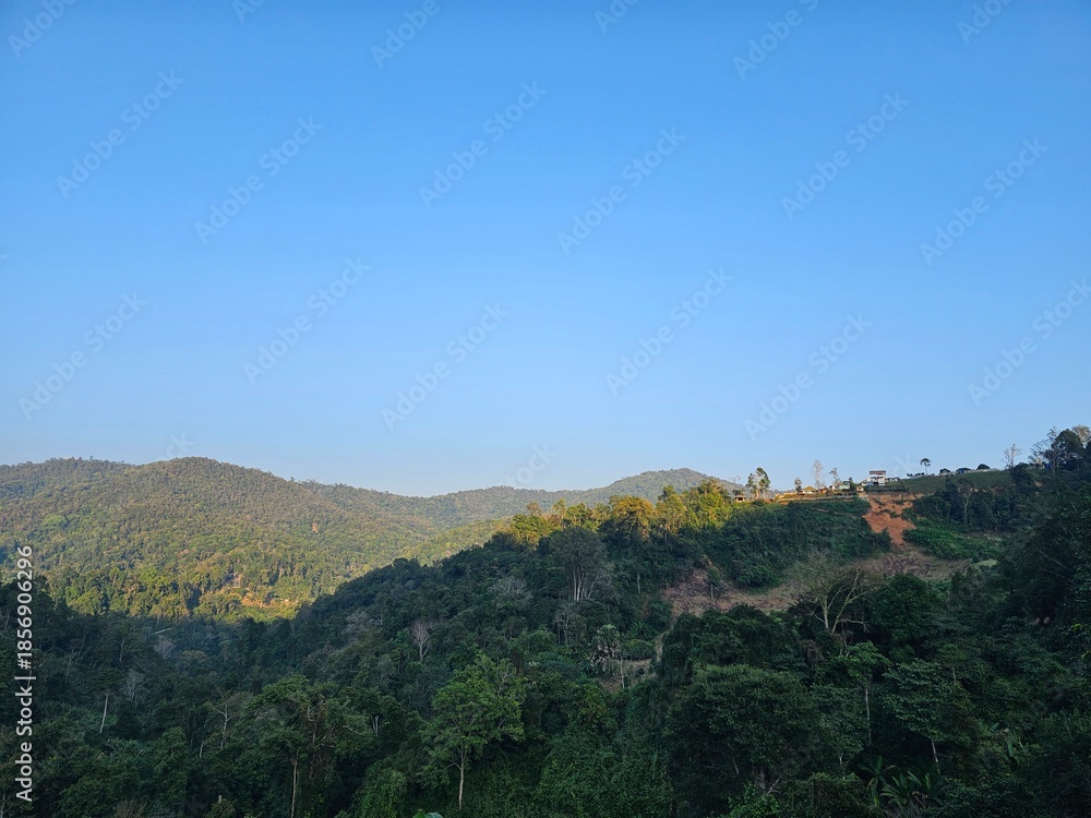 Obraz premium A scenic view of lush green mountains under a clear blue sky, showcasing the beauty of nature and tranquility.