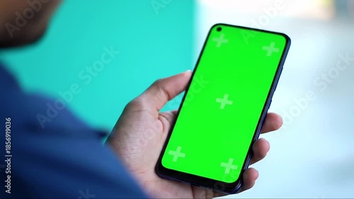 Person holding a smartphone with a green screen for easy content replacement, ideal for technology and app demonstrations.