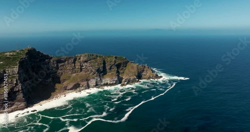 Aerial orbit establishing shot of the Cape of Good Hope peak. Rugged cliffs, vivid greenery, and coastal scenery on a sunny day. Ideal for travel, nature, landscape, and documentary projects