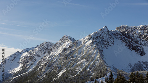 Beautiful panorama of high rocky mountains with snowy peaks against the blue sky and clouds. Brandnertal, Austria