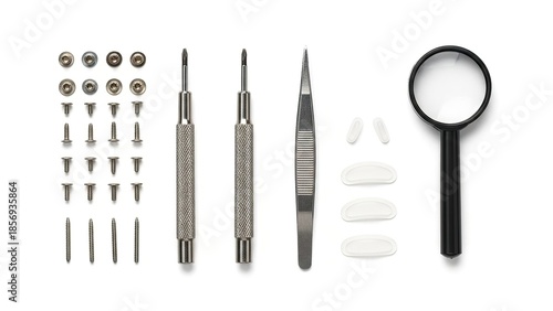 Detailed flat lay of assorted watchmaker's precision tools and small parts isolated on white background