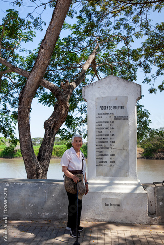 Wallpaper Mural Senior woman next to the Bolivar Stone inscribed with names and dates that narrate the route of freedom followed by Bolivar at the colonial Heritage Town of Santa Cruz de Mompox in Colombia. Torontodigital.ca