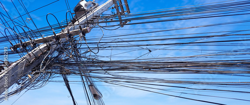 Tablou pe pânză Tangled and messy electrical power cables and wires on utility pole, symbolizing chaotic infrastructure, urban energy system disorder, wiring representing overloaded systems