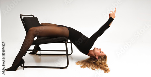 Foto Young charming lady girl laying on chair in black bodysuit, nylon tights pantyhose and shoes with high heels