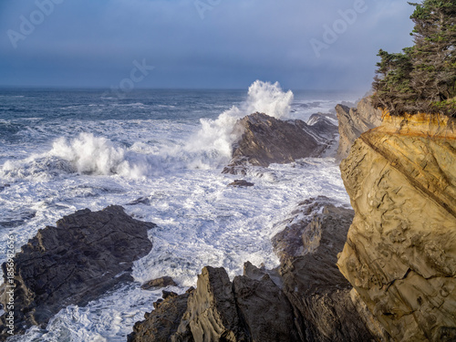 Waves crash on rocks below sandstone cliffs on the Pacific coast near Coos Bay, Oregon, USA