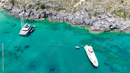 Aerial drone cinematic video of tropical paradise exotic island bay with emerald crystal clear beach resembling a blue lagoon visited by luxury yachts and sail boats in Caribbean destination