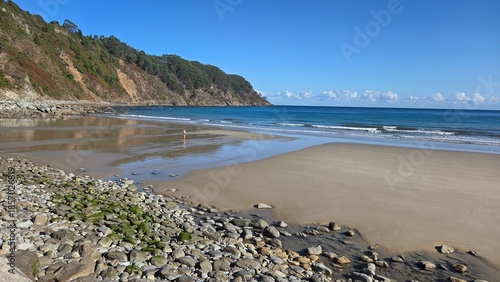 Foto Serene ocean coastline with sandy beach and rocky shoreline on a clear day