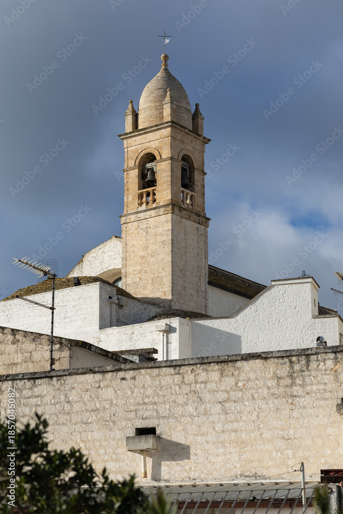 Fototapeta premium scenic view of a limestone church bell tower in puglia italy under a moody sky featuring traditional mediterranean architecture and ancient stone masonry details