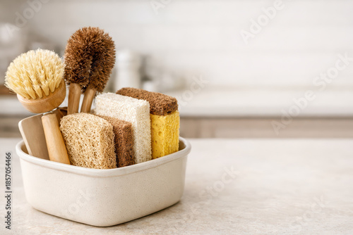 Natural cleaning brushes and sponges in container on kitchen countertop, eco friendly tools for household chores with soft bristles and textured surfaces for effective cleaning
