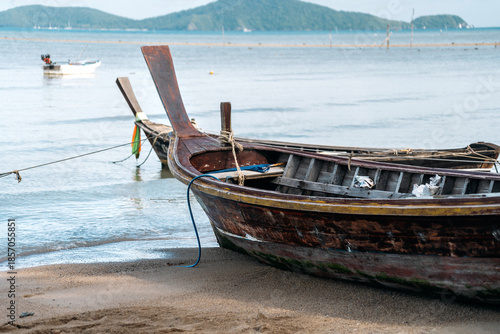 A watercraft is tethered to a rope on the beach, close to the water. The sky is picturesque, enhancing the art of morning travel by the lake.