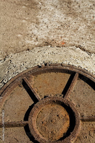 Wallpaper Mural Industrial Texture: Weathered Metal Manhole Cover on Sunlit Rough Concrete in Outdoor Setting Torontodigital.ca