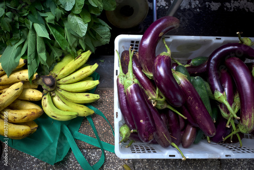 Yellow bananas, green vegetables and purple eggplant in traditional market, in Yogyakarta, Indonesia