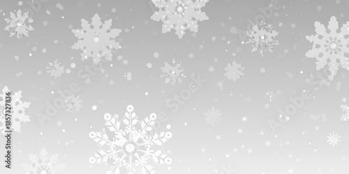 Delicate white snowflakes falling against a soft light gray winter background
