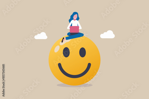 A woman working on a laptop atop a large smiling yellow sphere