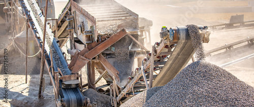 Vibrating screen stone crusher in operation. Crushing stones in a quarry for processing minerals, cement, limestone. Heavy and mobile equipment in a quarry for processing stone into building material.