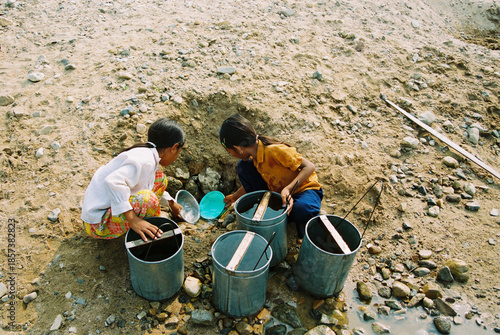 Photos Rural children digging for water in dry riverbed during drought conditions, film photography