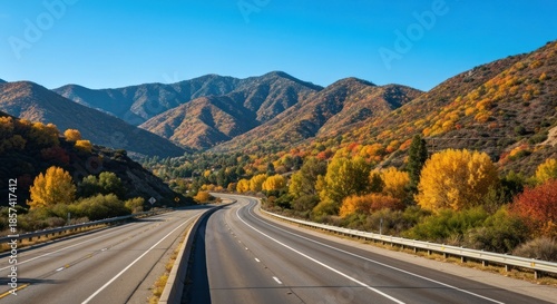 Highway winds through a vibrant autumn landscape. Mountains, colorful trees, and a clear sky