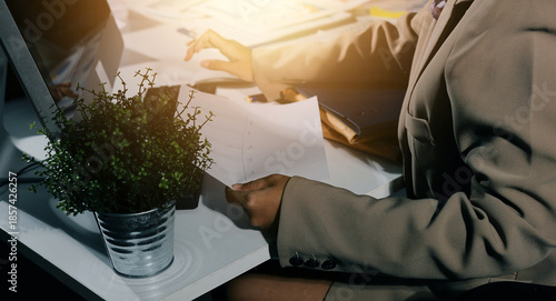 business documents on office table with tablet, smart phone and laptop and two colleagues discussing data