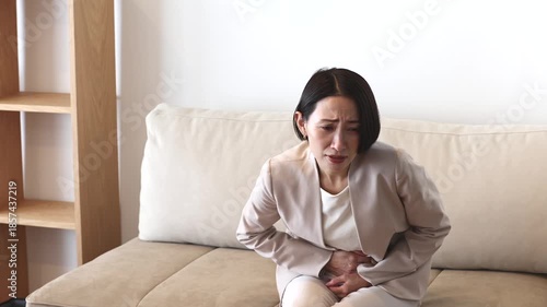 お腹を押さえるビジネスウーマン