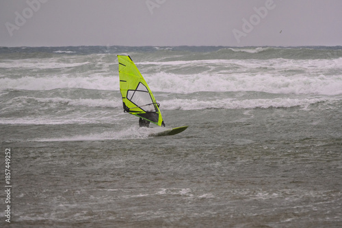 Tableau sur toile Water Sport Activity - Windsurfer Riding a Wave in Rough Sea on a Windy Day