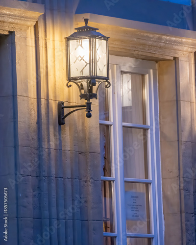 Elegant street lantern brightens up window during twilight in historic district
