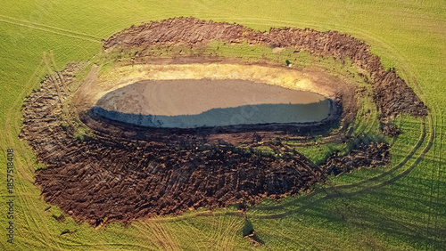 Aerial drone view of an artificial pond in a green agricultural field, showing land development and water management
