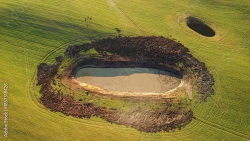 Aerial drone view of an artificial pond in a green agricultural field, showing land development and water management