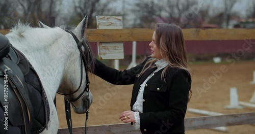 Woman touching white horse near paddock