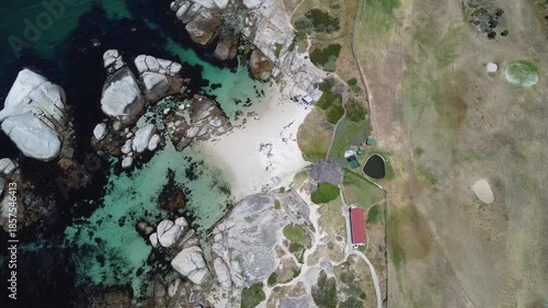 Aerial view of Simon's Town coastline near Boulders Beach, Cape Town, South Africa, featuring luxury residential houses, coastal road, turquoise ocean and mountains on a sunny summer day in Western Ca