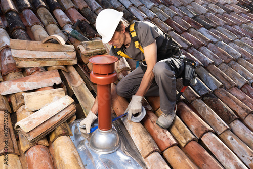 Roofer Installing Chimney on Residential Roof, applying waterproof sealing tape around Vertical Coaxial Boiler Flue