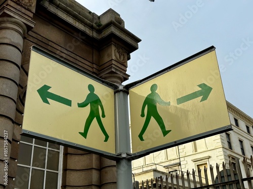 Richtungsweisende Schilder für Fußgänger in gelb mit grünen Männchen
