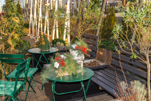 An outdoor café. On a green table are New Year's decorations with fir branches and red viburnum.