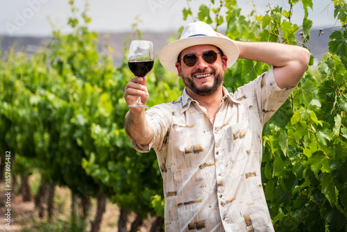 Bild auf Leinwand Hombre con sombrero y lentes degustando vino tinto y mostrando la copa, en un he