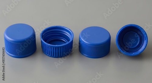 Four blue plastic bottle caps arranged on a gray surface image