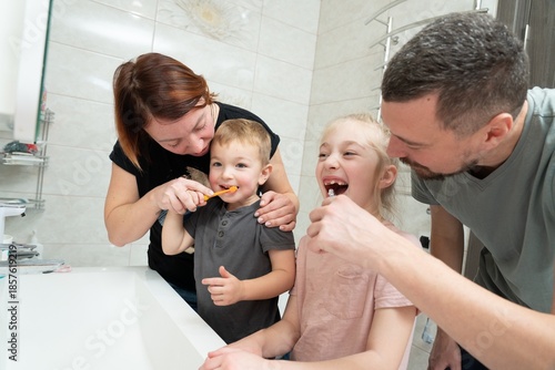 Parents helping to kids brush their teeth. Happy family