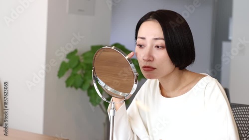 鏡を見て肌の調子を悩む気にする女性