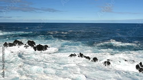 Waves of the blue Atlantic Ocean crashing into rocks on the coast. Porto Moniz, Madeira, Portugal