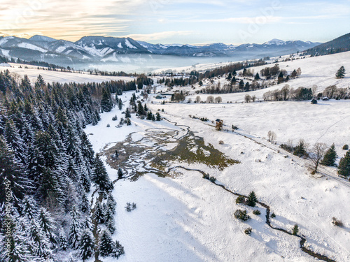 Aerial view of meandering Luznanka stream flowing through snowy landscape near Liptovska Luzna