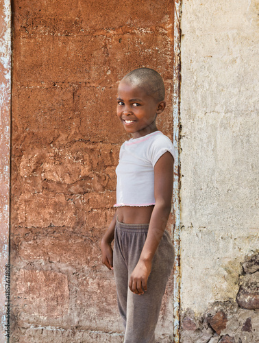 Happy African girl in rural Botswana village. Authentic humanitarian portrait for aid, charity, and development projects. Hope and resilience.
