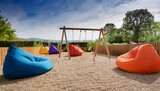 modern outdoor play area with colorful beanbag chairs and swings
