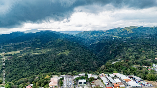 Panoramic Aerial View of Lush Mountain Forest and Industrial Zone Under Stormy Sky