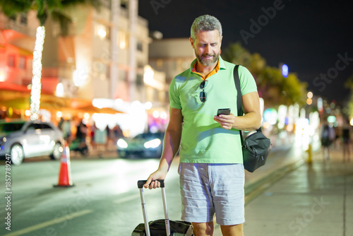 Canvas Print Tourist using phone in Miami streets at night