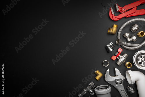 Plumbing tools and fittings on black background with copy space. Plumber equipment