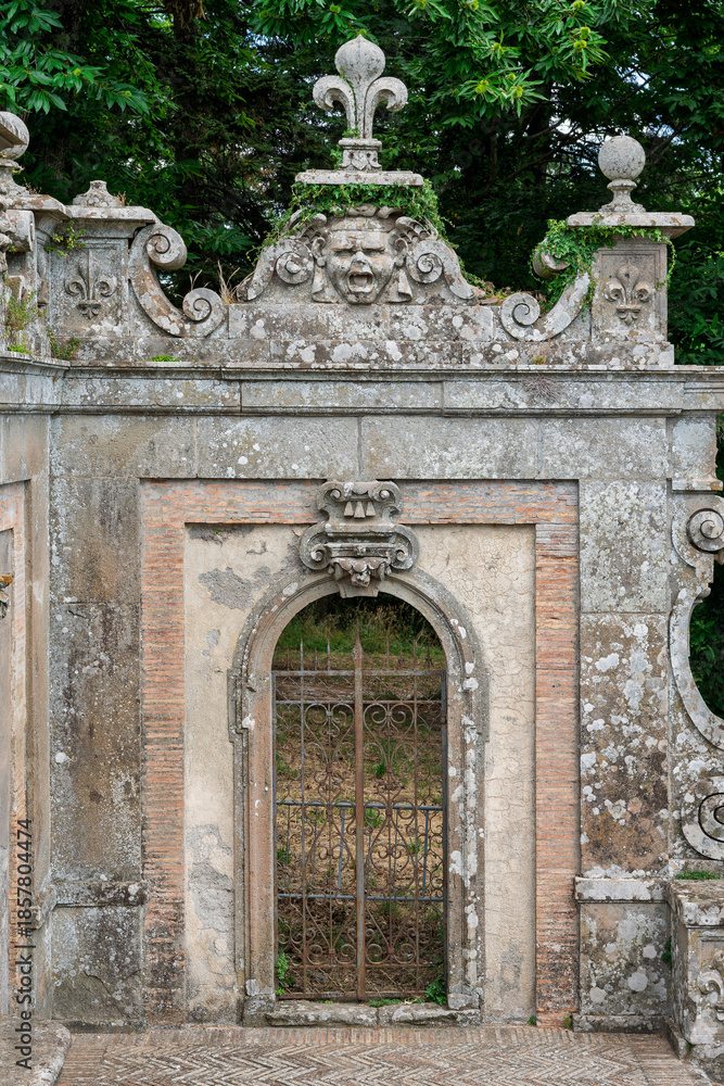 Obraz premium Italy - Caprarola - Palazzo Farnese - Ornate stone gateway with metal gate and fleur de lis in the gardens