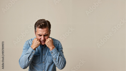 Angry man expressing frustration while standing against a neutral background  
