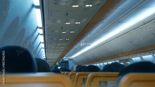 Commercial airplane cabin interior shakes and vibrates due to heavy turbulence during night flight. Passengers sit in rows experiencing stress and aerophobia while aircraft encounters rough weather.