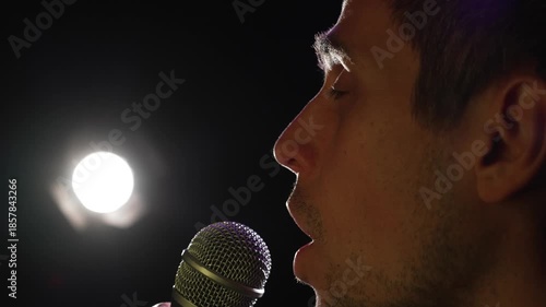 Man singing calm song on stage under spotlight