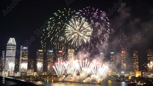 Green and blue fireworks explode over illuminated city skyline