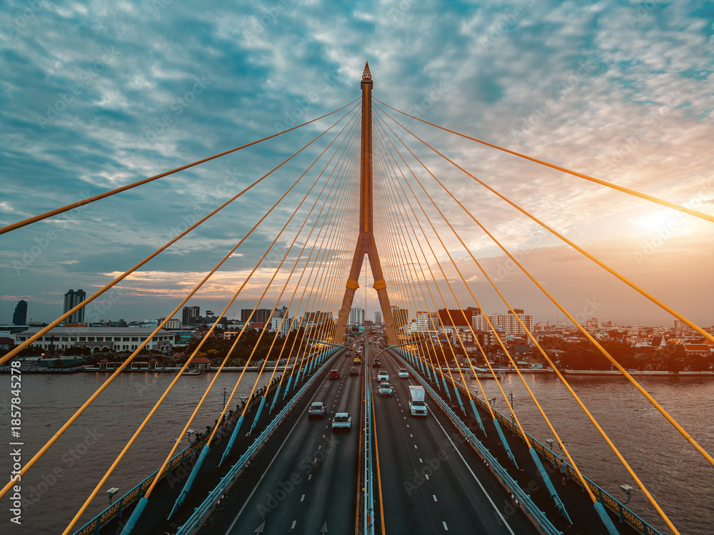 Obraz premium symmetric modern cable-stayed Rama VIII bridge over Chao Phraya river in Bangkok, symmetry perspective of contemporary suspension urban span connecting city skyline across Thai waterway